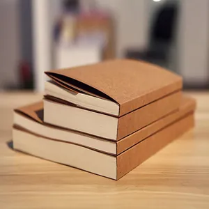 Detailed macro shot of stacked retro kraft paper blank sketchbooks on a natural wooden table