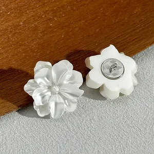 Close-up of white pearlescent flower-shaped shank buttons showing front and back detail