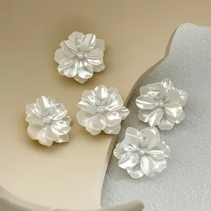 Detailed view of pearlescent white flower-shaped alloy buttons for clothing decoration