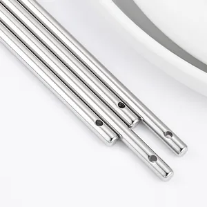 Gros plan de pendentifs cylindriques en acier inoxydable poli pour bijoux DIY.