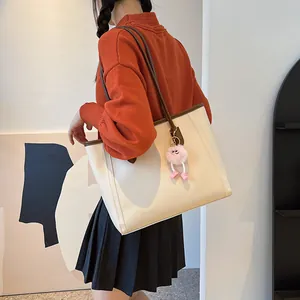 Detailed model shoulder shot of a large retro beige tote bag with a pink fuzzy keychain