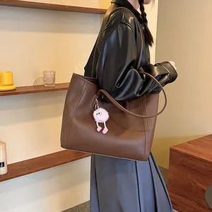 Detail view of stylish vintage brown large capacity tote bag carried by a fashion model