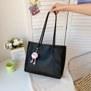 Large black vintage tote bag held by hand in a cozy room setting