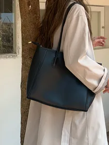 Close-up lifestyle view of a vintage large black leather tote bag on a model's shoulder