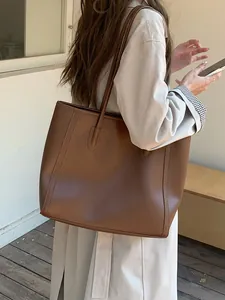 Large brown retro tote bag shown in a real-life commuting scene with Asian model
