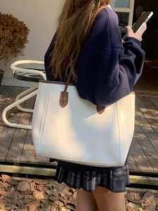 Stylish large white vintage tote bag with brown trim carried by a model in an outdoor setting