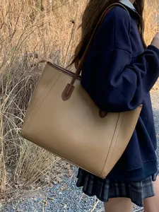 Vintage large capacity khaki tote bag for women shown on shoulder in outdoor setting