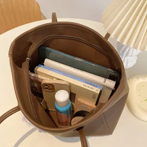 Detail view of a vintage brown tote bag's spacious interior filled with daily essentials.