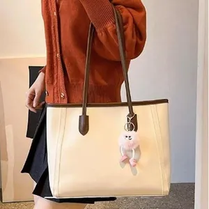 Large cream vintage tote bag with brown straps and pink mascot charm shown on model