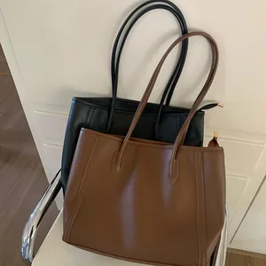 Vintage large capacity faux leather tote bags in black and brown colors shown on chair