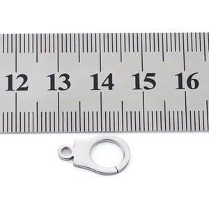 Macro view of polished stainless steel handcuff charm against a metal ruler for scale
