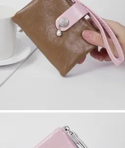 Detail view of pink and brown leather wallet featuring crackle texture and pearl charm.