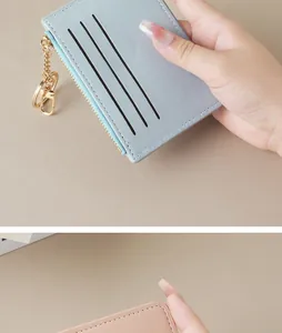 Close-up view of slim light blue card holder with gold zipper and keychain detail