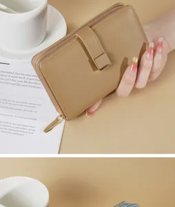 Primo piano di un portafoglio da donna in pelle marrone chiaro tenuto in mano con stile