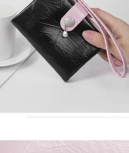 Detailed view of women's short wallet with pearl charm and cracked leather texture