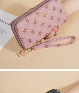 Close-up detail of a pink floral patterned double-zipper long wallet with a wrist strap