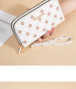 Close-up detail of a white floral pattern long wallet with double zippers and wrist strap