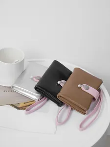 Elegant women's short wallets with cracked leather texture, pearl charm, and wrist strap