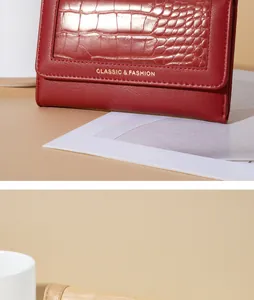 Detailopname van bordeauxrode krokodillenprint en gouden letters op deze dames portemonnee