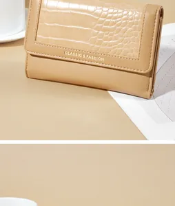 Detailweergave van een beige portemonnee met krokodillenprint en tekstuele details.