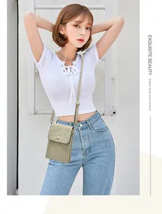 Aziatisch model toont kleine saliegroene crossbody telefoontas met witte achtergrond.