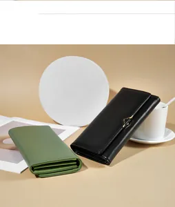 A lifestyle showcase of black and green long leather wallets on a warm, minimalist backdrop.