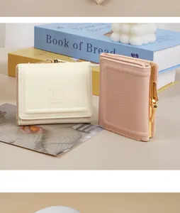Close-up detail of cream and dusty pink short wallets with rabbit embossing and gold metal clasp.