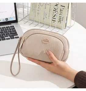 Close-up of a beige double-zipper ladies wristlet held in hand with leather texture