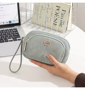 Detailed view of a mint green double zipper clutch bag with a wristlet strap held