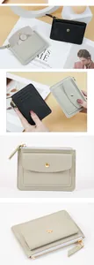 Macro view of compact PVC wallet showing zipper and snap-button pocket details.