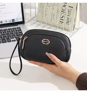 Detail view of a black textured leather clutch bag featuring double zippers and wrist strap