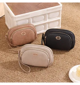 Three stylish double-zipper clutch bags in beige, black, and brown textured leather.