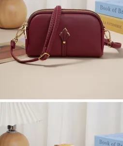 Détail de la pochette en cuir rouge vin avec fermoir tulipe doré et double fermeture éclair