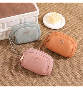 Detailed view of three women's double-zipper clutch wallets in pink, orange and grey