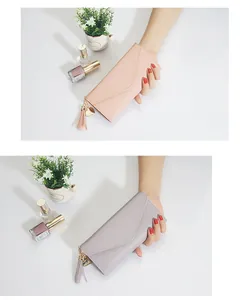 Detalle de carteras largas y delgadas en rosa y gris con colgante de corazón y borla