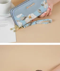 Close-up detail view of blue long floral embroidery wallet with elegant wrist strap