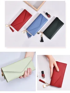 Detalle de carteras largas para mujer en varios colores con dijes de corazón y borlas