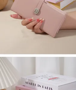 Élégant portefeuille long en similicuir rose avec boucle de fermeture tenu à la main.