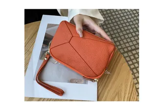 Close-up of a premium orange leather wristlet bag with a geometric stitching pattern detail