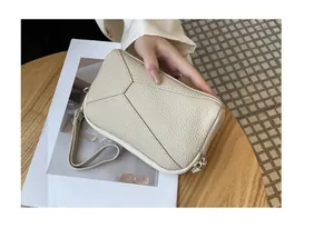 Detail view of a cream-colored textured leather wristlet wallet with geometric stitching