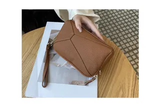 Genuine leather brown phone pouch with wristlet strap held in hand showing texture.