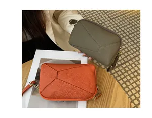 Close-up of small genuine leather crossbody bags in vibrant orange and olive green