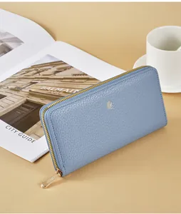 Close-up detail of blue litchi grain leather wallet with gold-tone zipper and logo