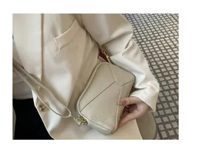 Close-up view of a premium cream lychee grain leather phone bag with gold hardware.