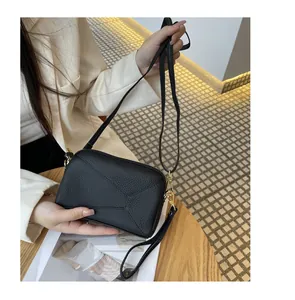 Close-up of black genuine leather phone bag with geometric stitching and gold hardware.