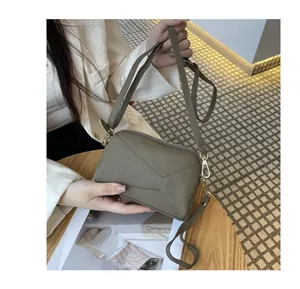 Detailed view of a sage green genuine leather crossbody phone bag with pebbled texture.