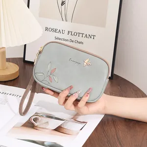 Detailed view of the blue floral print double zipper clutch bag with wrist strap