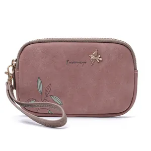 Close-up detail of mauve floral double zipper clutch bag featuring a gold bird logo