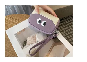 Dettaglio di un portamonete in pelle viola con simpatici occhi e cinturino da polso