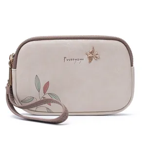 Detailed front view of Prettyzys beige wristlet wallet with bird charm and leaf print